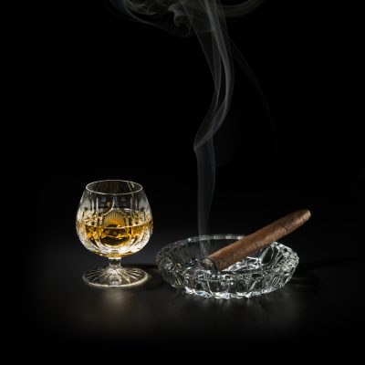 Cognac and smoking cigar on black background